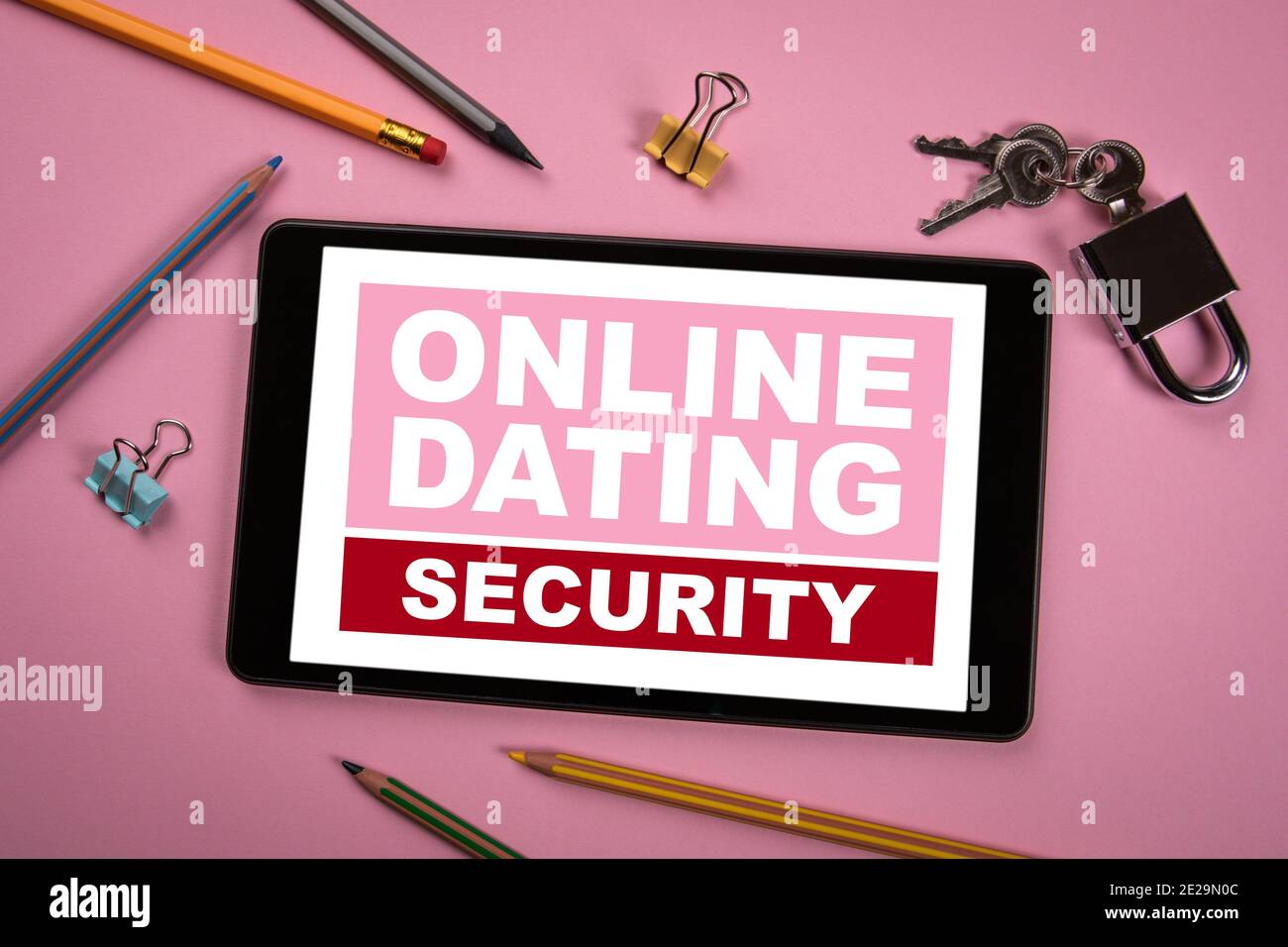 Online Dating Security Concept. Tablet, lucchetto e cancelleria su sfondo rosa. Foto Stock