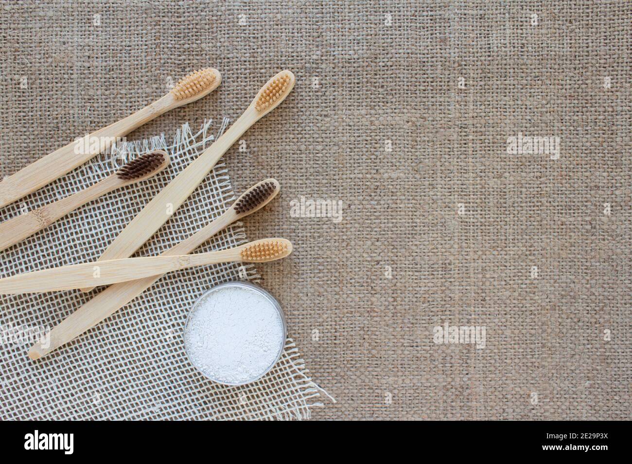 Prodotti essenziali naturali per il bagno in casa zero rifiuti - spazzolini da denti in bambù e caolino dentifricio o polvere di dente fatta con ingredienti naturali su rustico Foto Stock