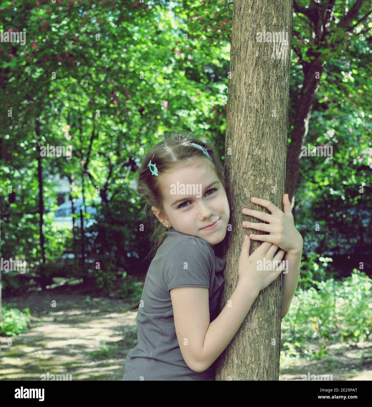 Concetto di giovane ragazza che abbraccia un albero nel parco, ritratto vista frontale Foto Stock
