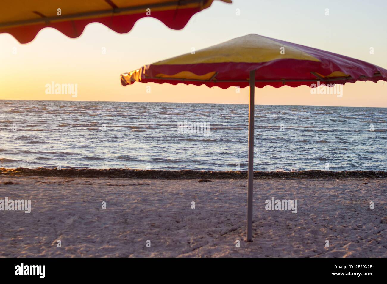 Ombrellone colorato sulla spiaggia sabbiosa vuota all'alba Foto Stock