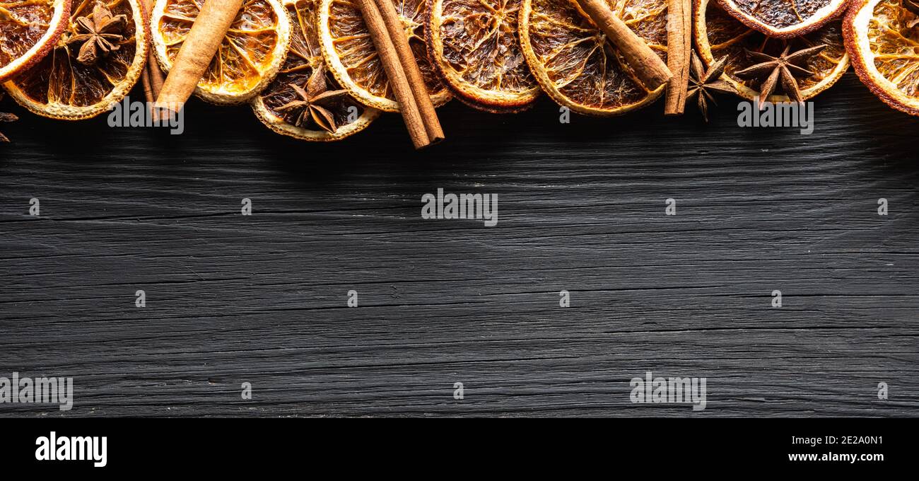 Sfondo di legno nero con arance secche, cannella e stelle di anice. Ripresa dall'alto. Sfondo e texture. Foto Stock