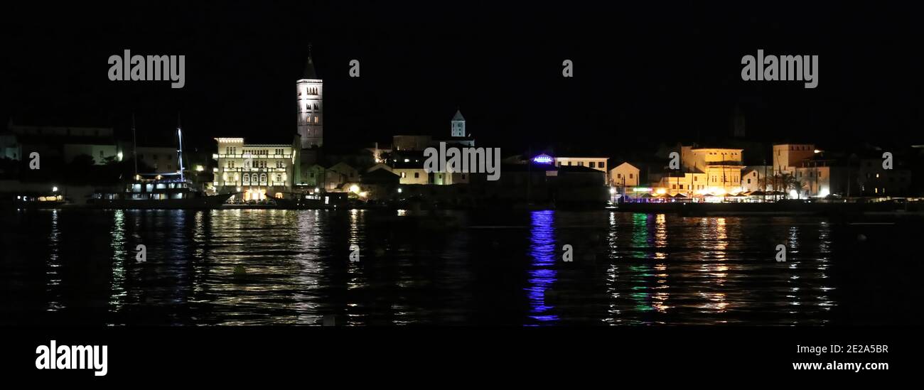 Croazia, regione del Quarnero, isola di Rab, vista panoramica del porto di Rab di notte con luci che si riflettono sull'acqua Foto Stock