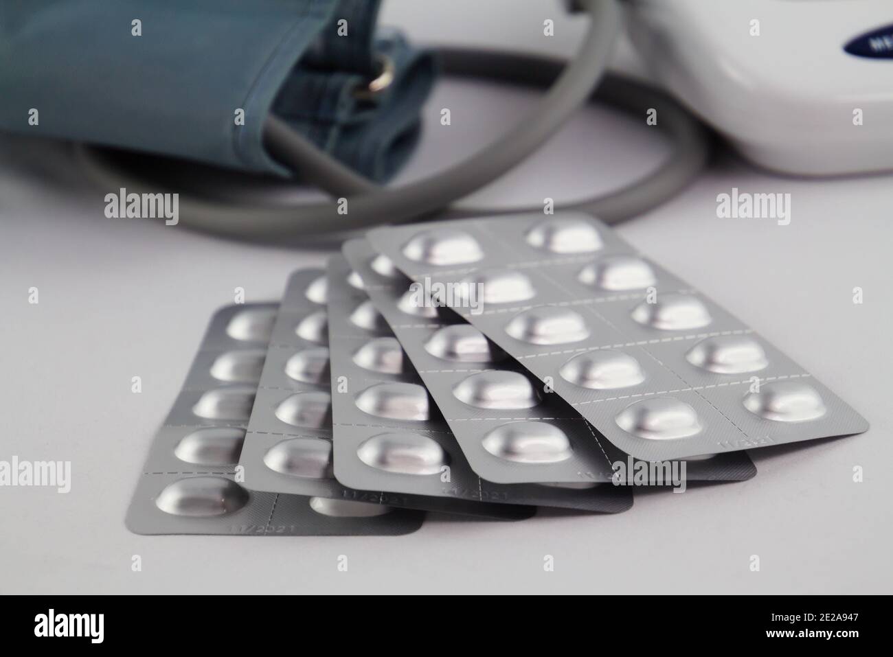 Fuoco selettivo sulle pillole mediche contro l'ipertensione e un moderno defocalizzato monitoraggio della pressione sanguigna in background, concetto di trattamento contro hi Foto Stock