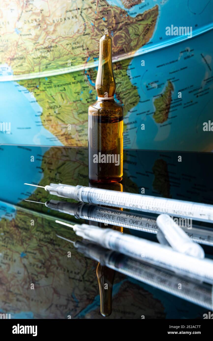 Vaccinare e salvare il mondo. Un set di vaccini, siringhe e attrezzature da laboratorio di fronte al globo. Inizio della vaccinazione di massa Foto Stock