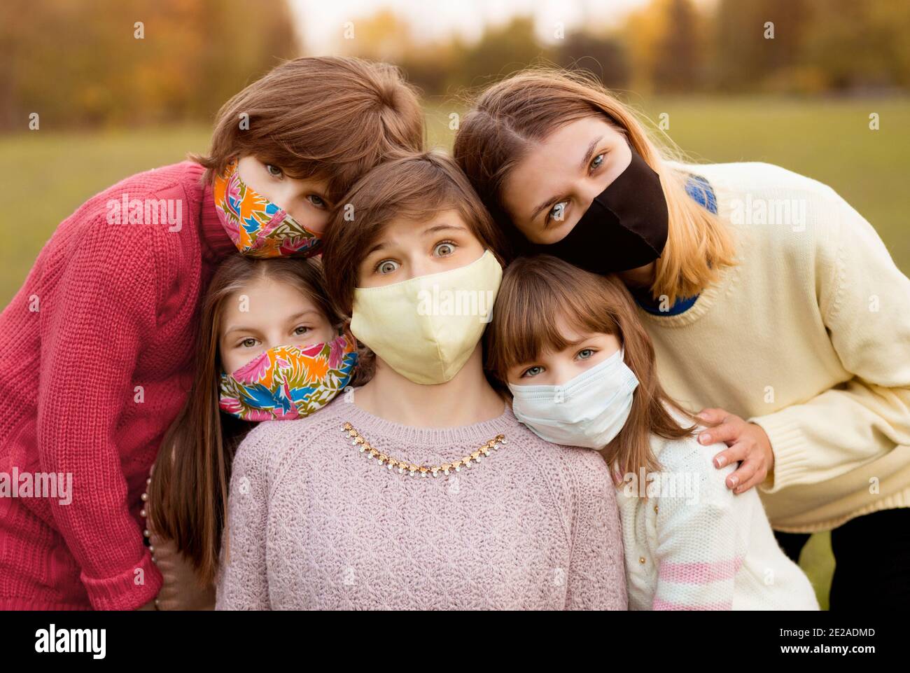 Gruppo di giovani allegri in maschere di faccia che si incontrano all'aperto durante la pandemia covid-19. Nuovo concetto di stile di vita e generazione z Foto Stock