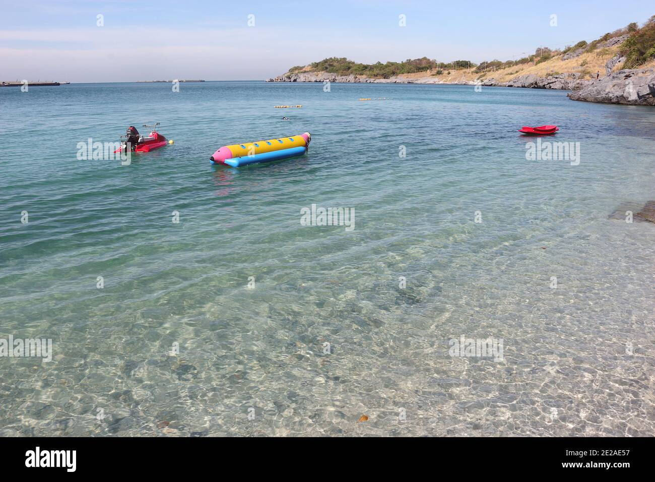 Immagine della vista del mare e del cielo. In primo piano sono presenti una barca rossa e una banana boat gialla. E le montagne sullo sfondo. Foto Stock