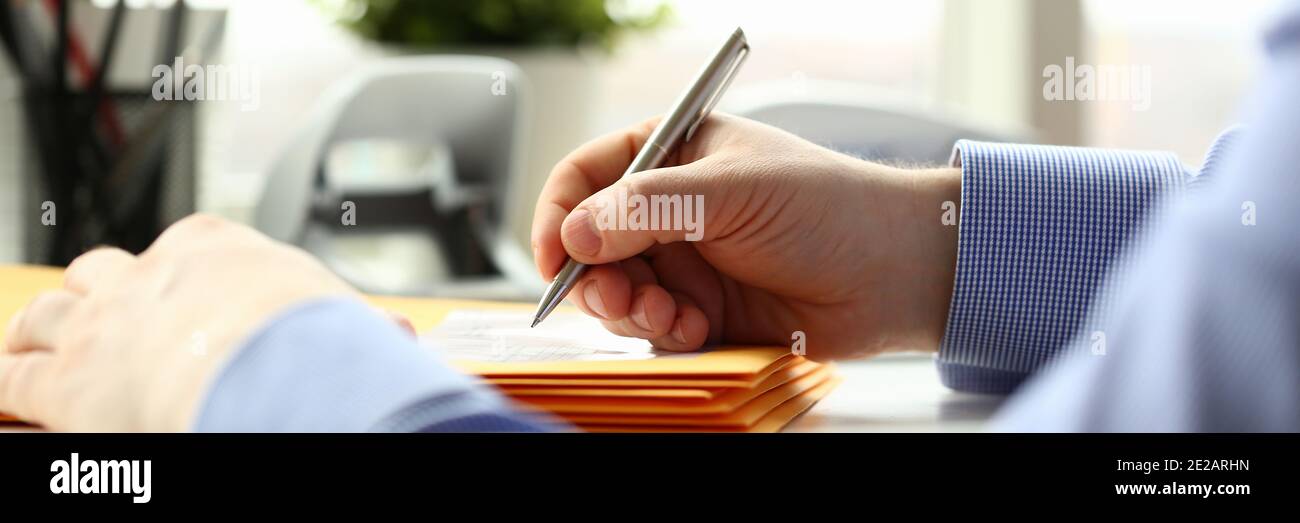 Uomo che firma i documenti alla scrivania in ufficio Foto Stock