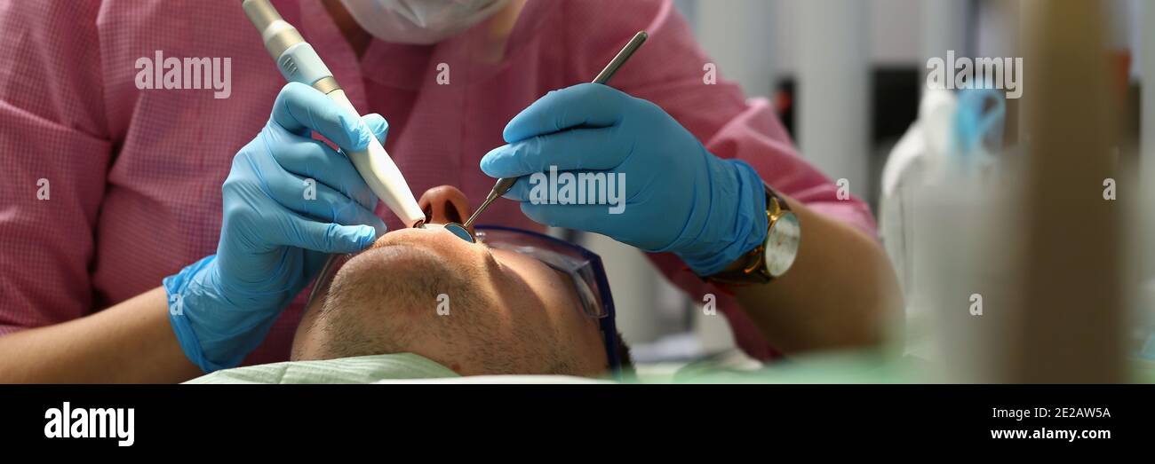 Giovane dentista concentrato che fa il controllo dei denti in clinica Foto Stock