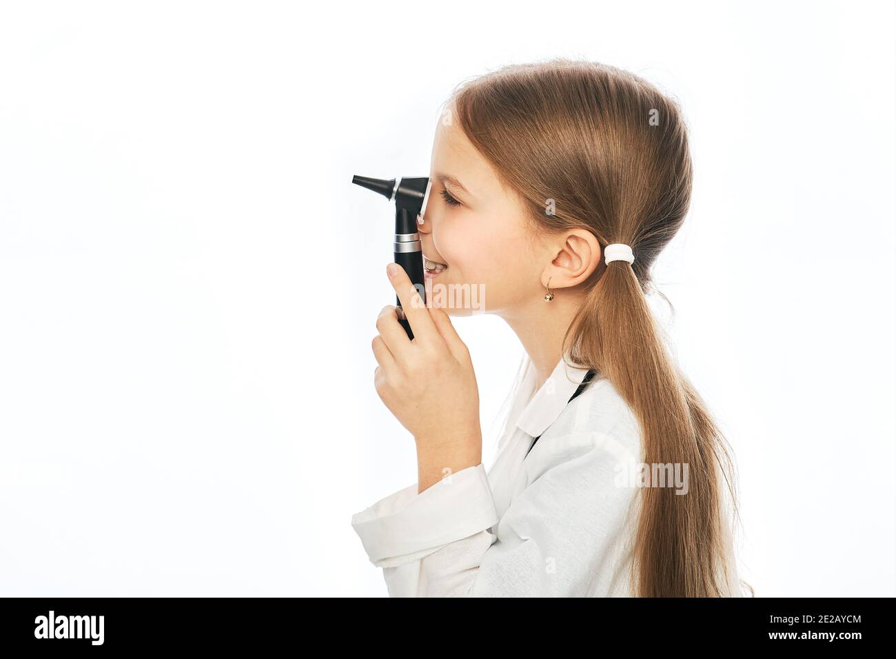 Cute bambino che gioca medico oftalmologo con un oftalmoscopio. Vista laterale, sfondo bianco Foto Stock