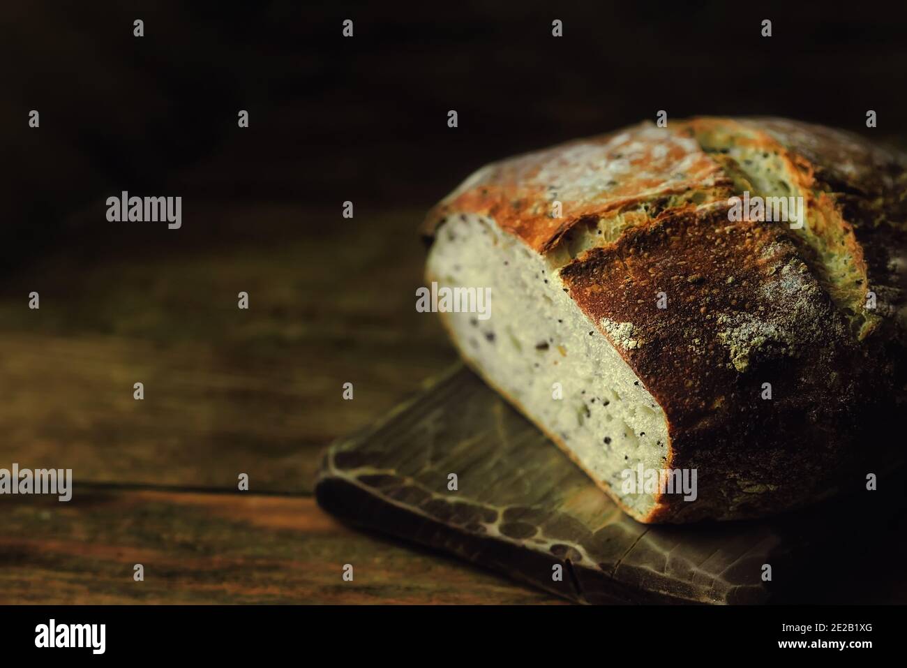 Una pagnotta di pane rotondo fatto in casa su uno sfondo scuro con spazio da copiare. Dolci privi di lievito con i propri cereali. Foto Stock