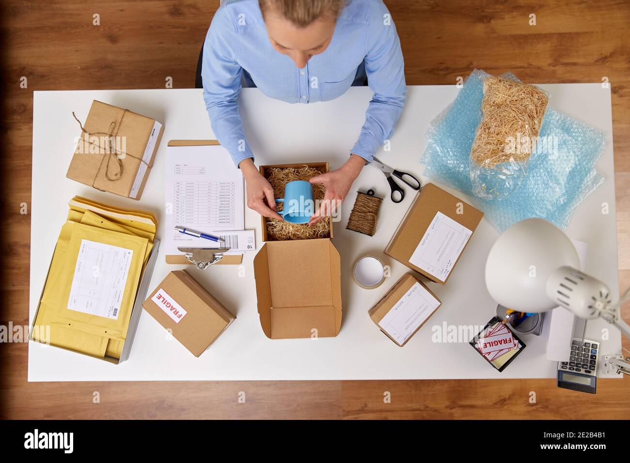 donna che imballa la tazza alla scatola del pacco all'ufficio postale Foto Stock