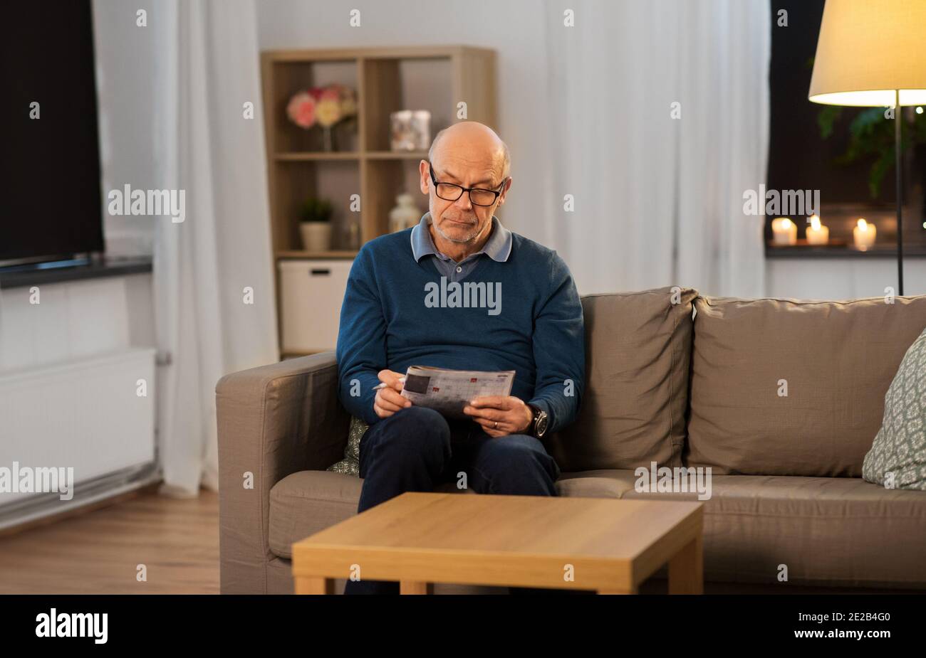 uomo anziano in occhiali risolvere crossword a casa Foto Stock