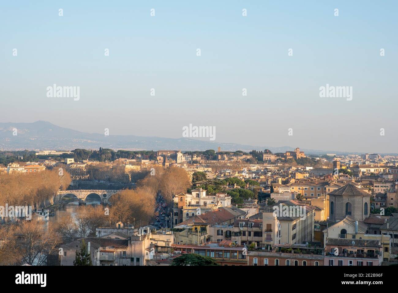 Vista sui tetti di Trastevere, Roma, Italia, fino al Tevere e alle chiese sul colle Aventino in mezzo, e le colline oltre la città. Foto Stock