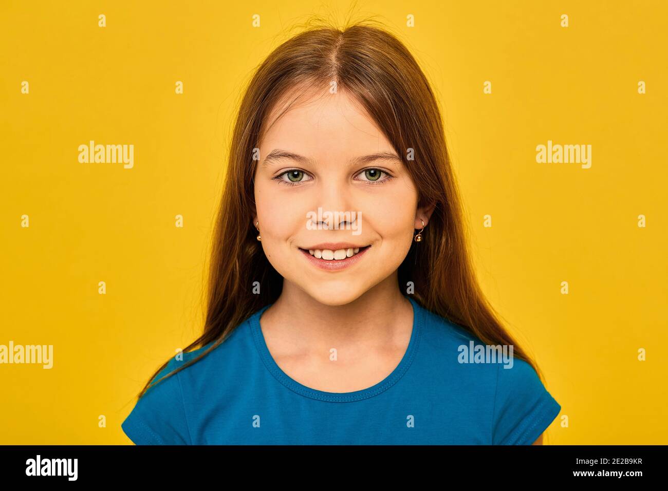 Ragazza positiva che indossa una t-shirt blu, etnia caucasica, sorridente e guardando la macchina fotografica, su sfondo oro fortuna Foto Stock