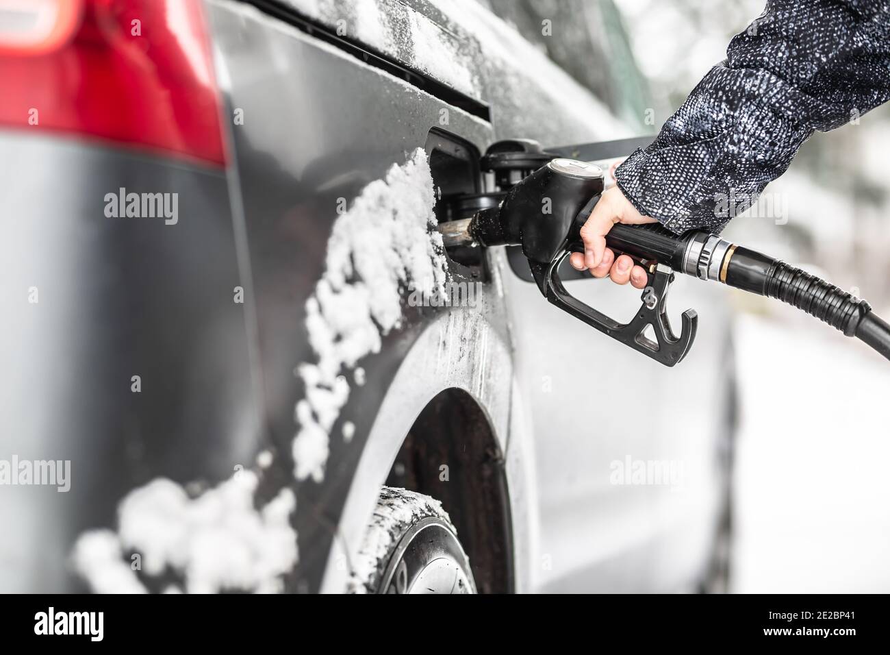 Rifornimento del serbatoio del carburante durante l'inverno con resti di neve sulla vettura. Foto Stock