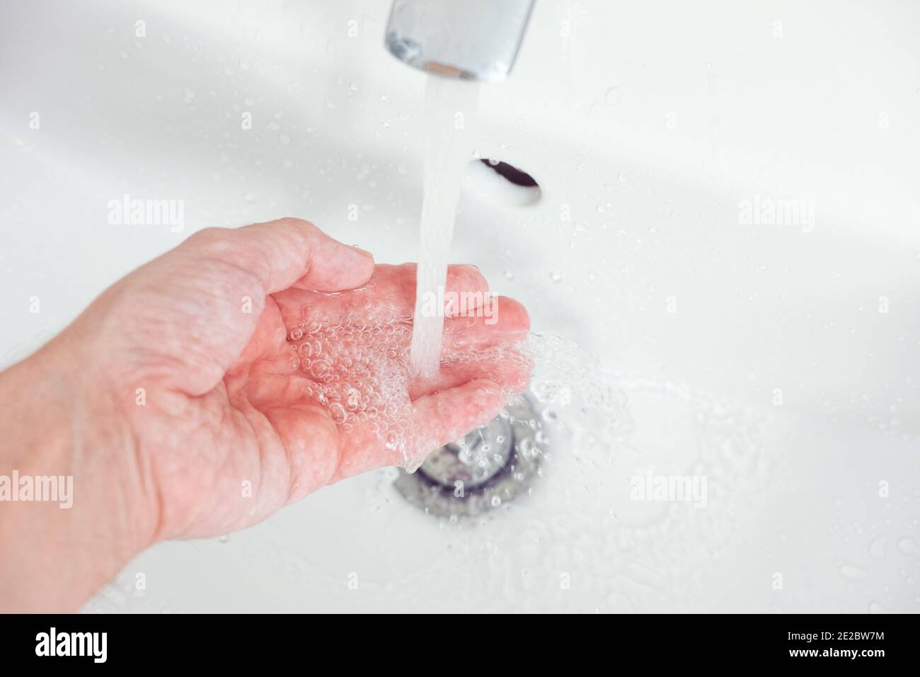 Un uomo che gli lava la mano con acqua di rubinetto. Primo piano. Foto Stock