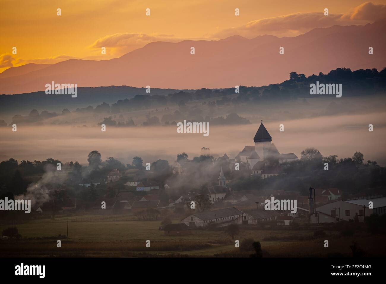 La chiesa fortificata di Hosman all'alba sotto uno spesso strato di nebbia e fumo. Foto scattata il 3 ottobre 2020 presso Hosman, regione della Transilvania, R. Foto Stock