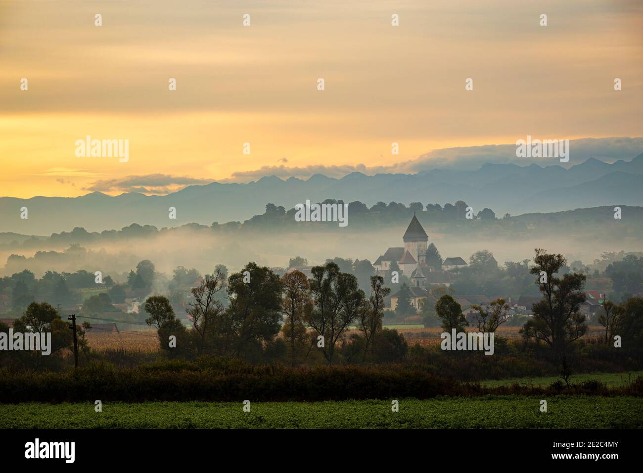 La chiesa fortificata di Hosman all'alba sotto uno spesso strato di nebbia e fumo. Foto scattata il 3 ottobre 2020 presso Hosman, regione della Transilvania, R. Foto Stock