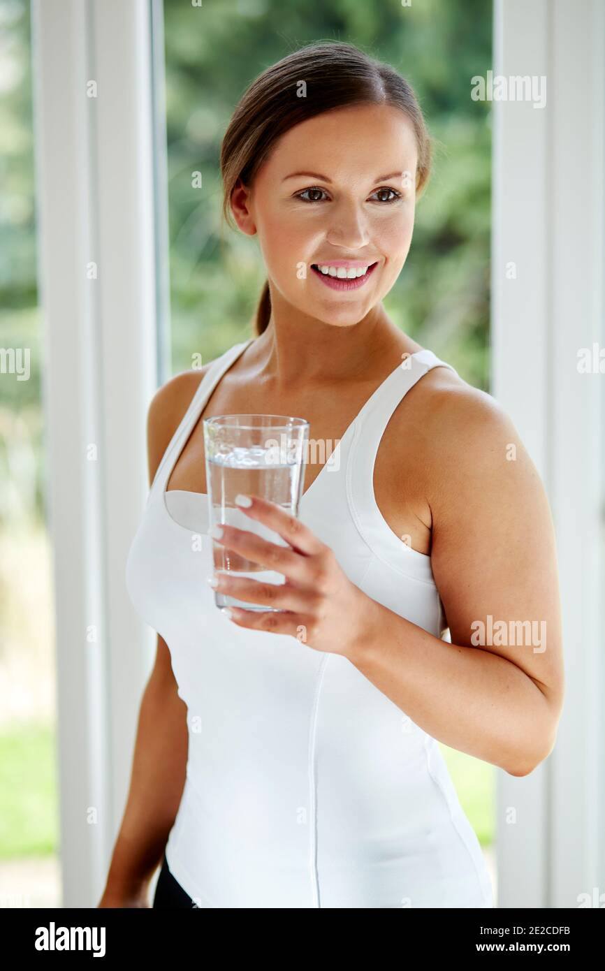 Donna con in mano un bicchiere di acqua Foto Stock