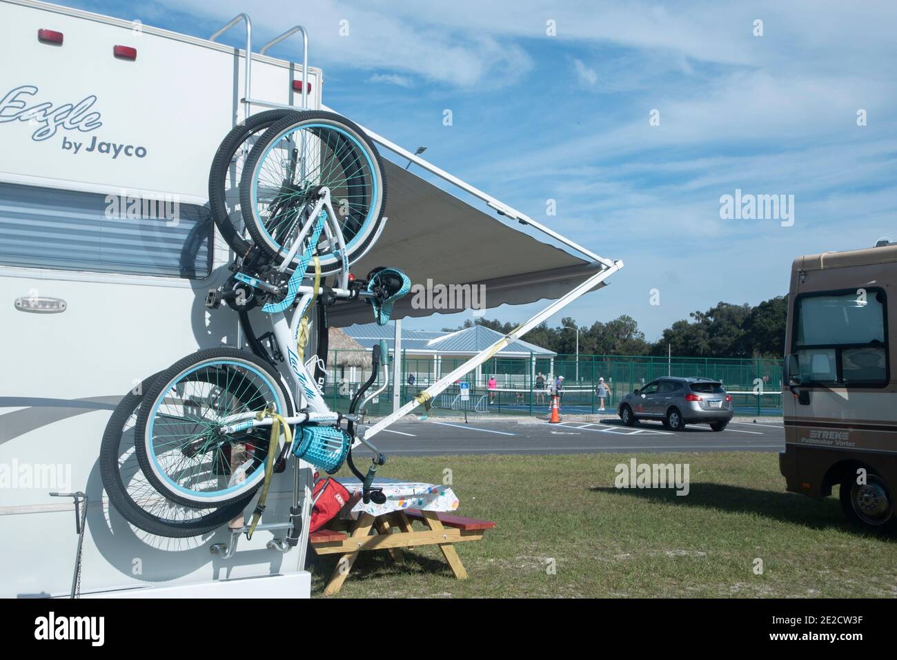 Le biciclette sono appese da un camper e le donne giocano a picklball in background a Webster, Florida. Foto Stock
