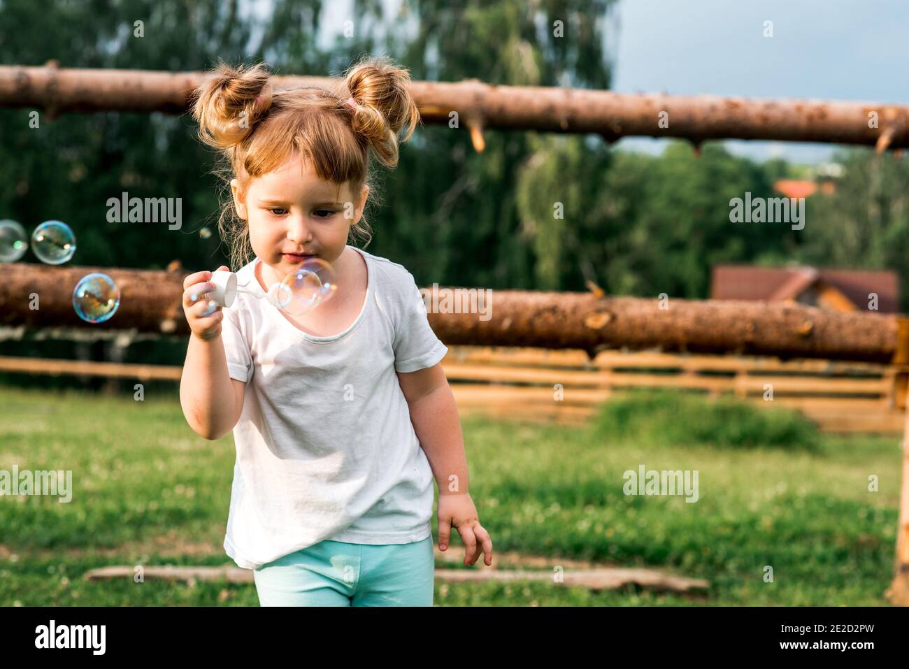 Bambino dolce che cerca di prendere il sapone bubble.Summer nel villaggio. Tramonto caldo. Felice infanzia. Foto Stock