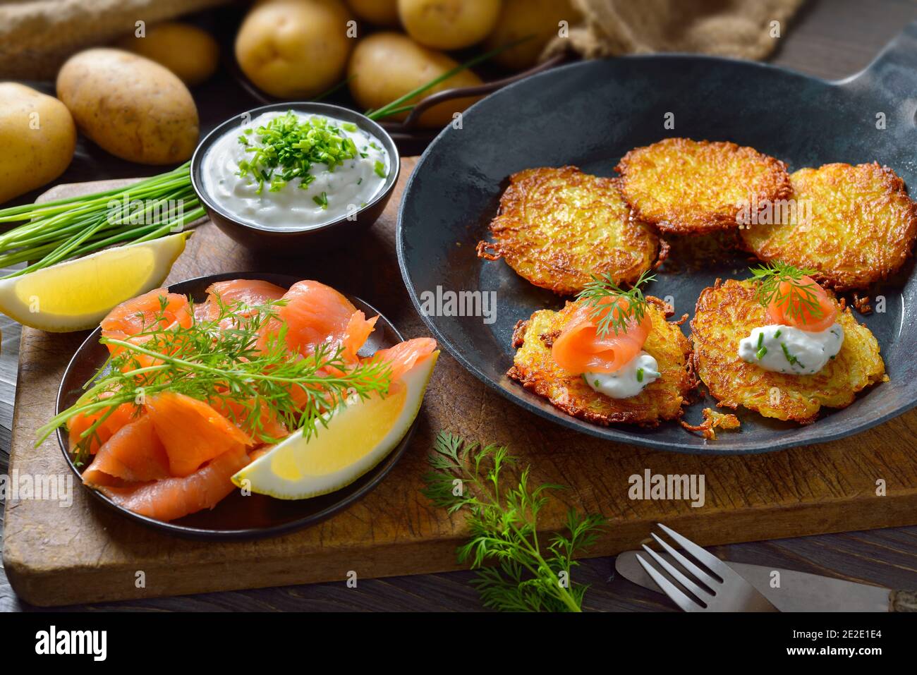Frittelle croccanti di patate con salmone affumicato e quark di erba cipollina serviti in una padella da stiro Foto Stock