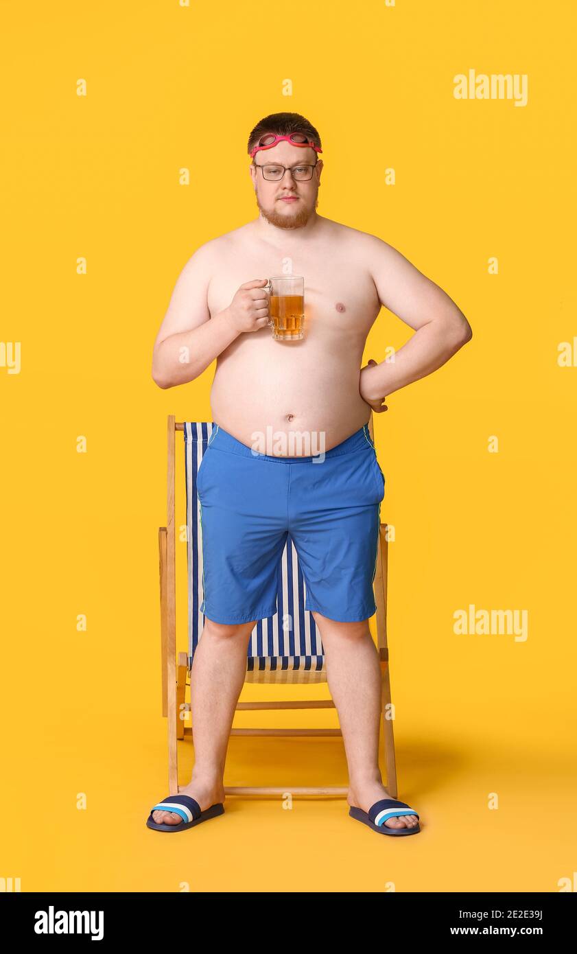 Uomo sovrappeso in costume da bagno e con bicchiere di birra su sfondo  colorato. Concetto di perdita di peso Foto stock - Alamy