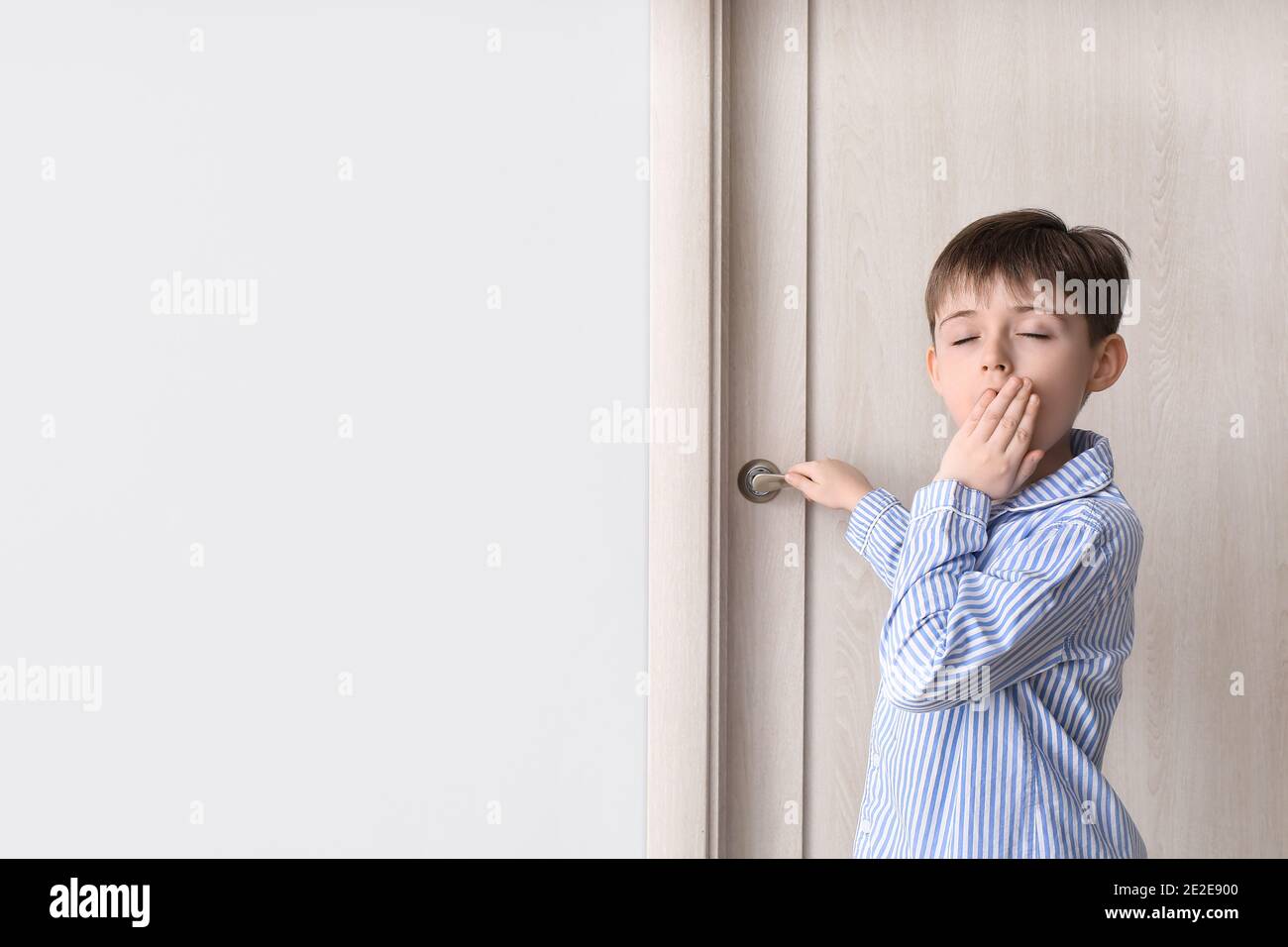 Bambino assonnato in piedi vicino alla porta chiusa Foto stock - Alamy