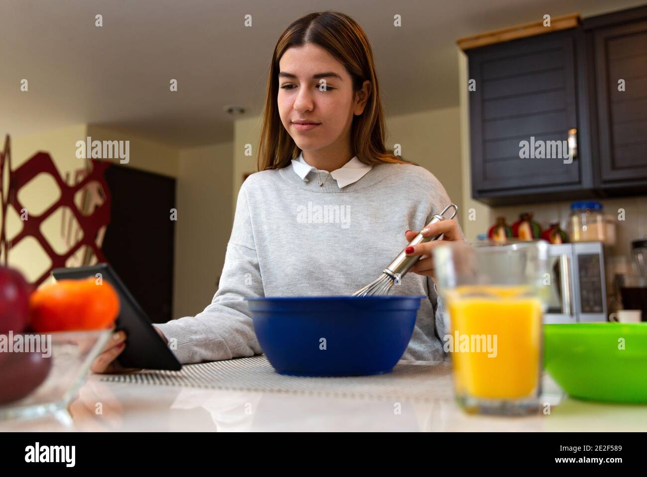 Giovane donna sta imparando a cucinare con la sua tavoletta. Sta sorridendo. È in cucina. Foto Stock