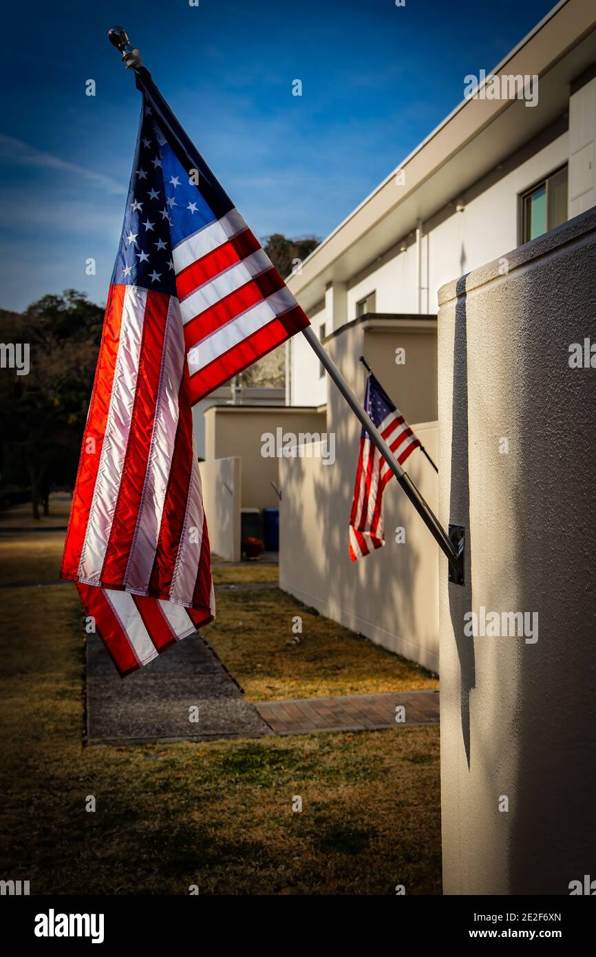 Bandiere americane volano orgogliosamente, prendendo il sole del mattino, in un cortile di fronte. Foto Stock
