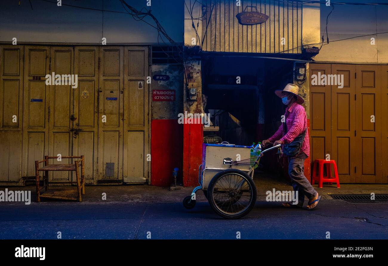 Un venditore di frutta mobile spinge il suo carrello intorno alla zona Talat noi di Bangkok, Thailandia Foto Stock