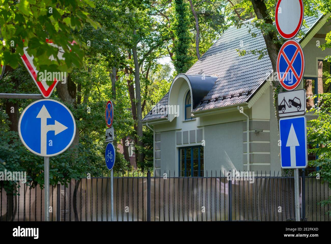 Molti cartelli stradali su piccola strada vicino casa privata. Concetto di sicurezza stradale. Messa a fuoco selettiva. Foto Stock