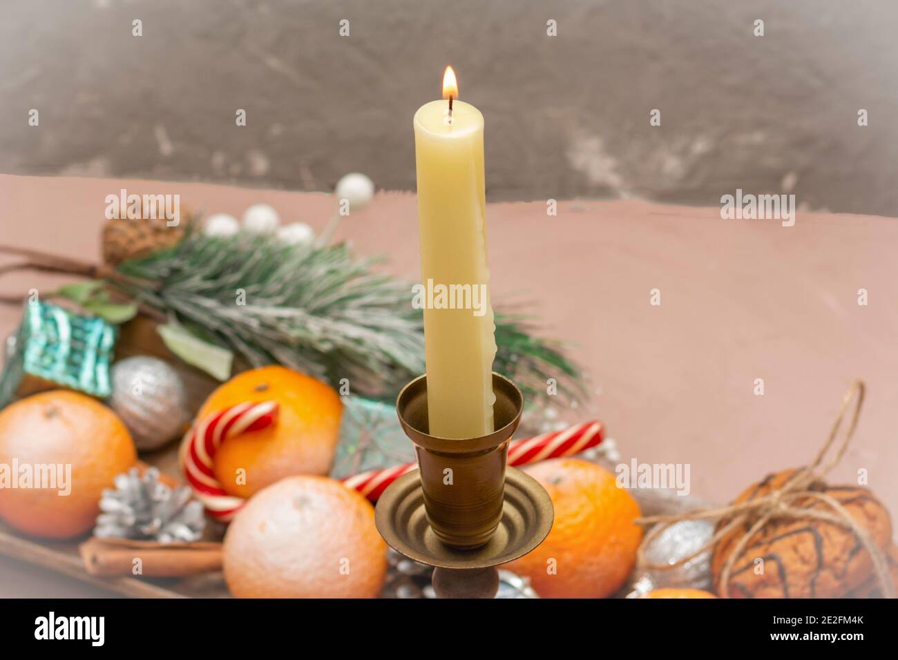 Candela di Capodanno sul tavolo con tangerini e dolci. Messa a fuoco selettiva, sfondo sfocato. Foto Stock