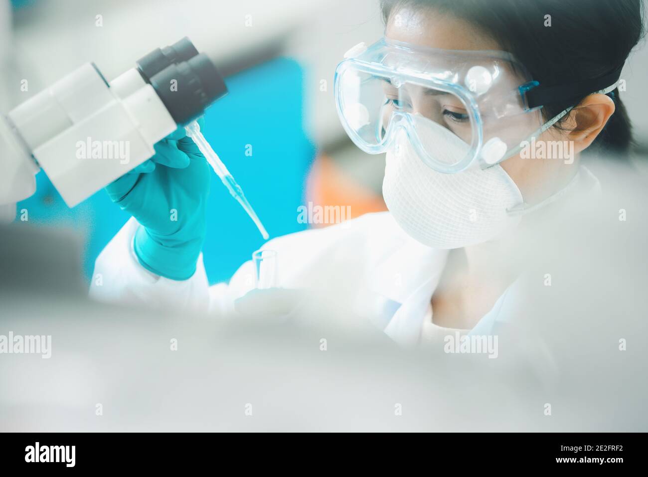 Medico o scienziato che utilizza una pipetta per far cadere un campione a. provetta in laboratorio di ricerca medica o in laboratorio scientifico Foto Stock