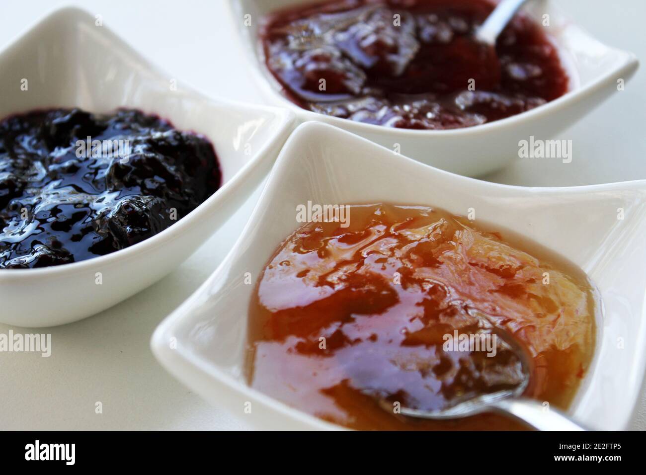 Una selezione di tre diverse confetture in piccole ciotole bianche. Foto Stock