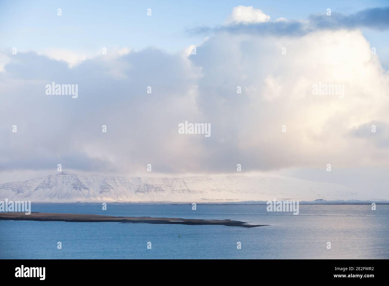 Paesaggio costiero islandese. Montagne innevate sotto il cielo nuvoloso durante il giorno d'inverno. Reykjavik, Islanda Foto Stock