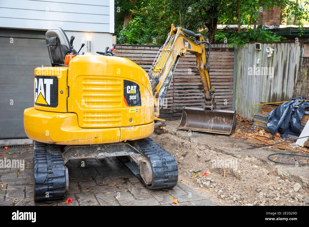 Miniescavatore scavare meccanicamente una trincea per riparare una rottura Tubo di drenaggio, Sydney, Australia Foto Stock