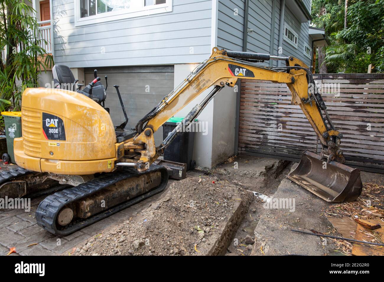 Miniescavatore scavare meccanicamente una trincea per riparare una rottura Tubo di drenaggio, Sydney, Australia Foto Stock