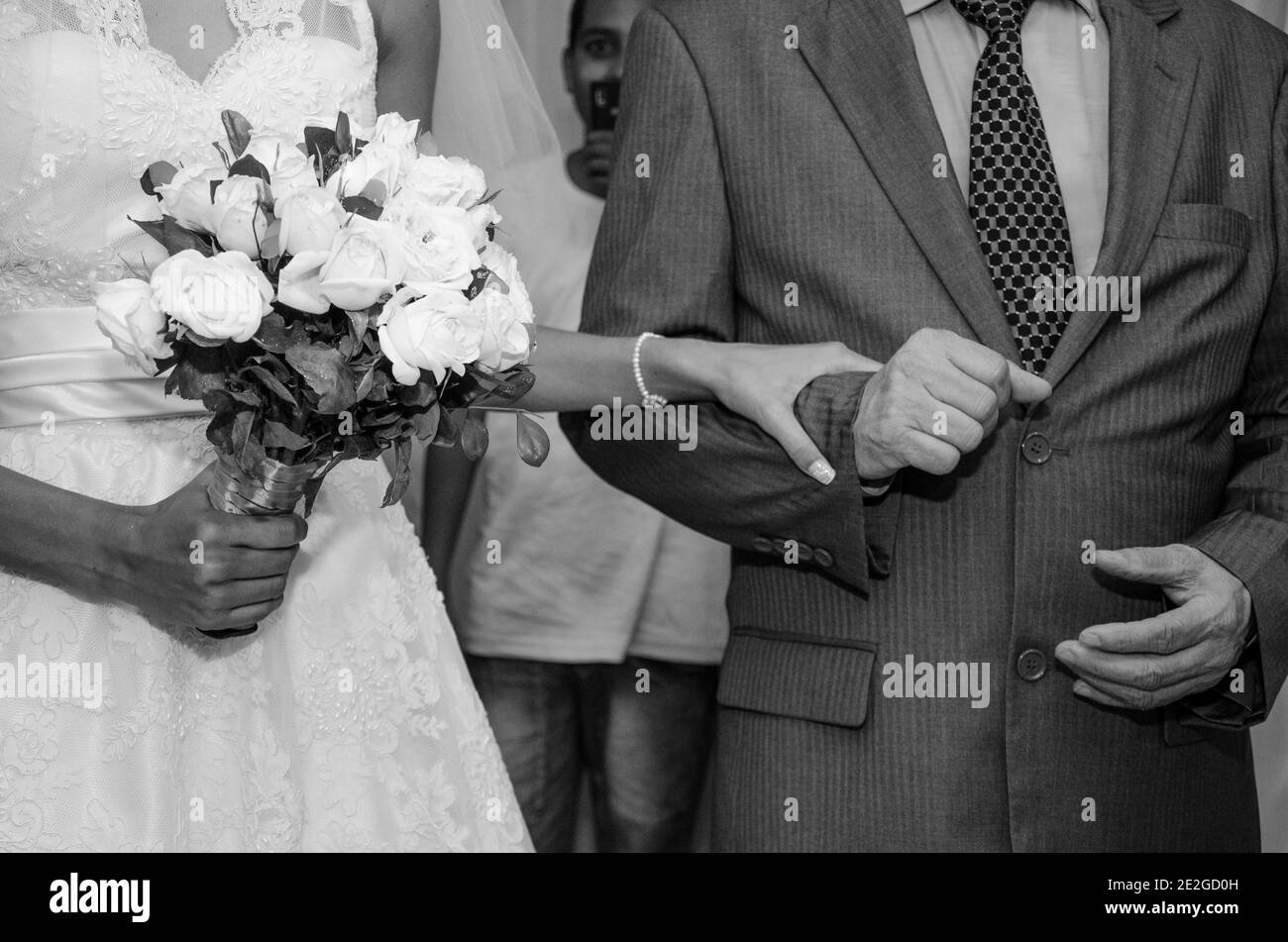 Colpo in scala di grigi di una sposa che tiene il braccio di lei marito Foto Stock