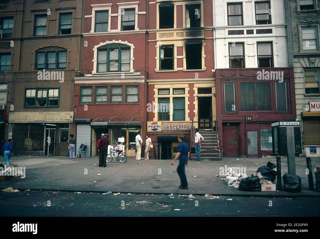 Stati Uniti, New York: Atmosfera in una strada di Harlem nel 1981. Passersby e residenti di Harlem su un marciapiede fuori un negozio di alimentari, 'generi alimentari Foto Stock