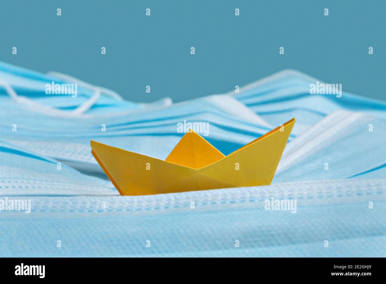 Imbarcazione origami gialla su maschere facciali blu monouso Foto Stock