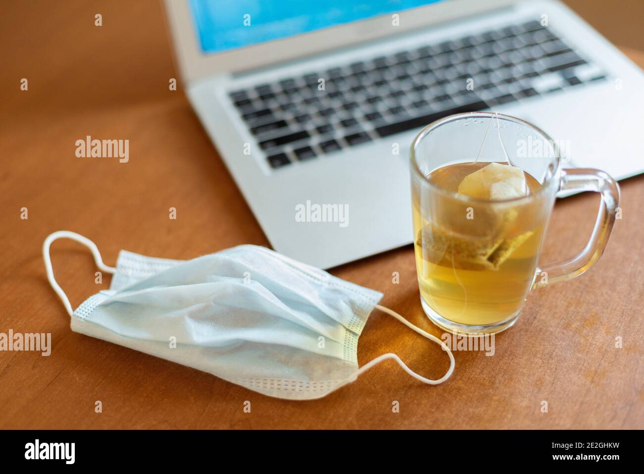 Maschera protettiva per il viso e tè al computer portatile Foto Stock