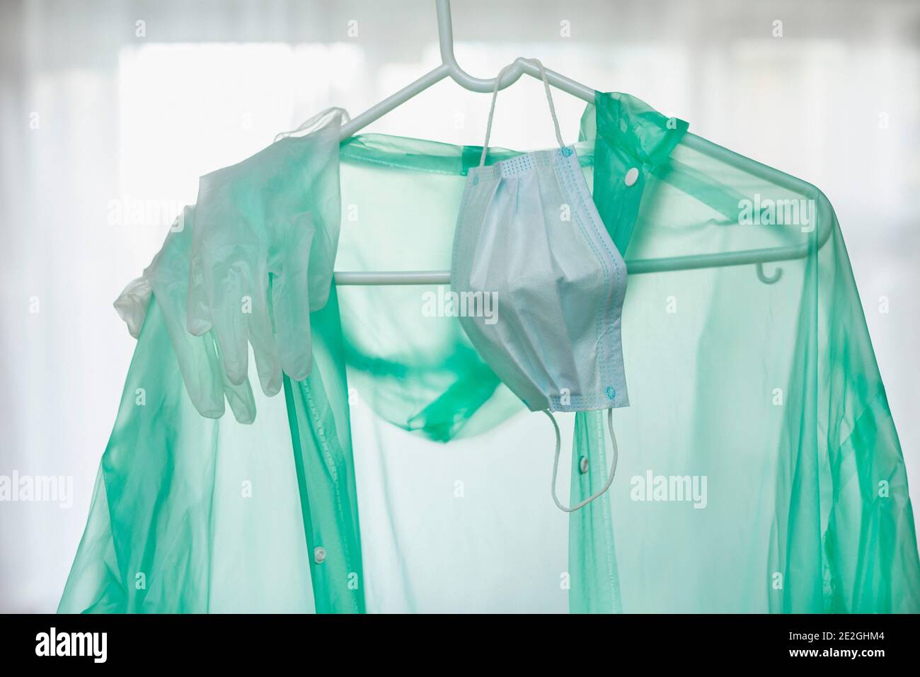 Tuta protettiva, guanti e maschera per il viso appesi all'appendiabiti Foto Stock