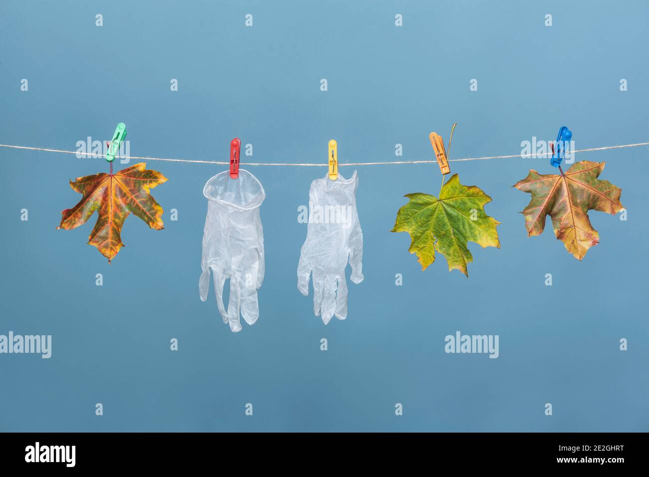 Guanti di protezione appesi su stendiabiti con foglie autunnali Foto Stock