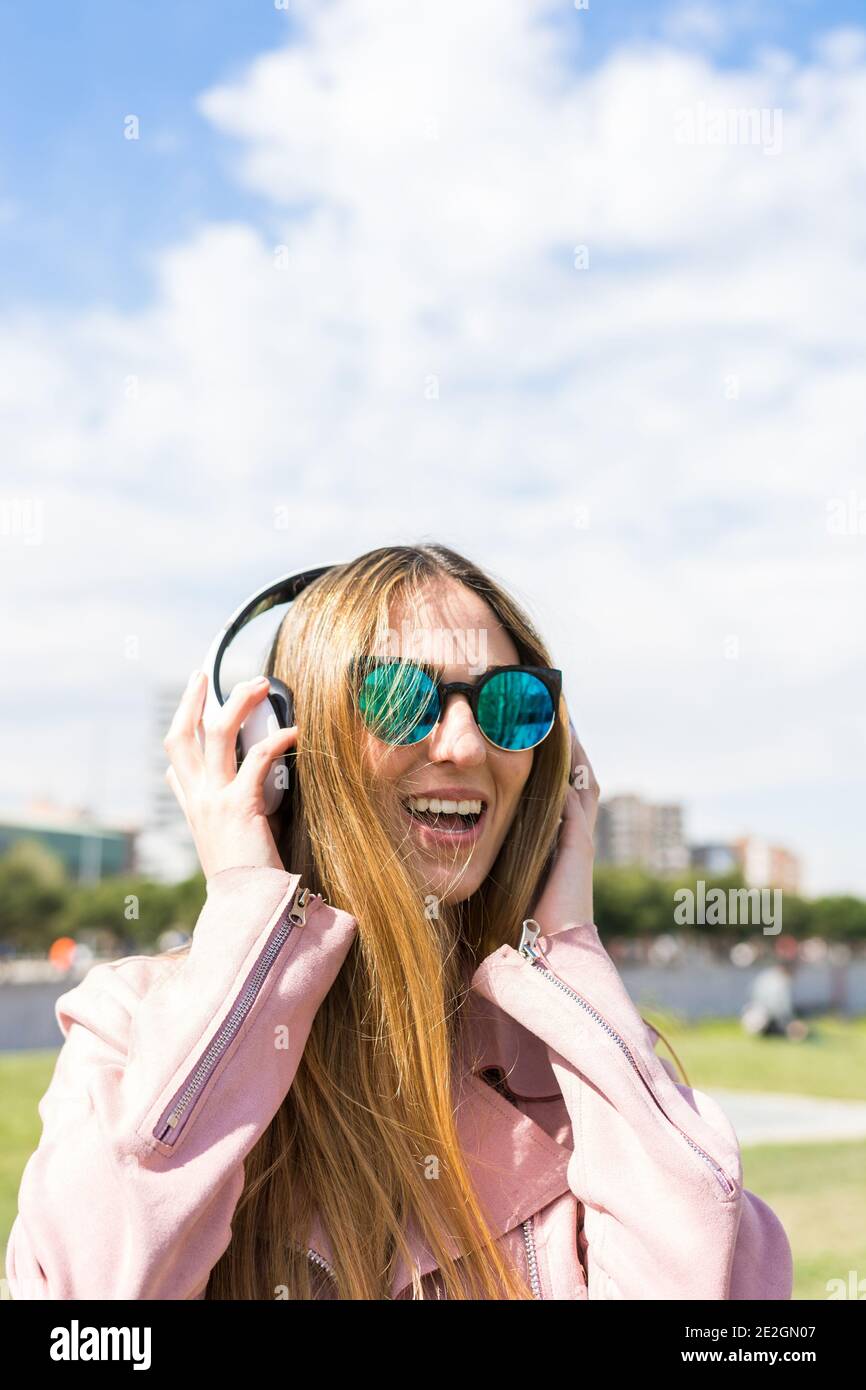 Giovane e felice ragazza sta ballando mentre ascolta la musica con le sue cuffie in primavera Foto Stock