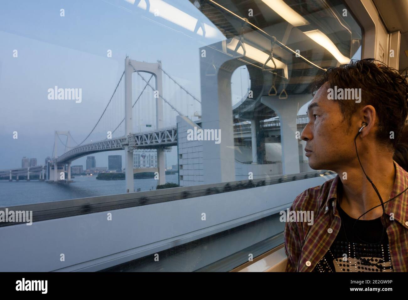 Un uomo guarda fuori da una finestra sul treno Tokyo Yurikamome Line al Rainbow Bridge. Tokyo Giappone. Foto Stock