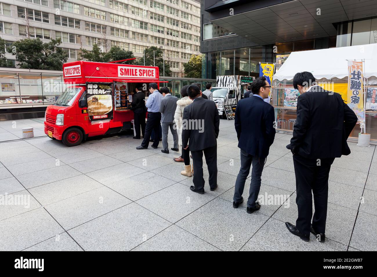 Salari giapponesi si allineano per un pranzo al curry da un furgone in Sankai Plaza a Otemachi, Tokyo, Giappone. Foto Stock
