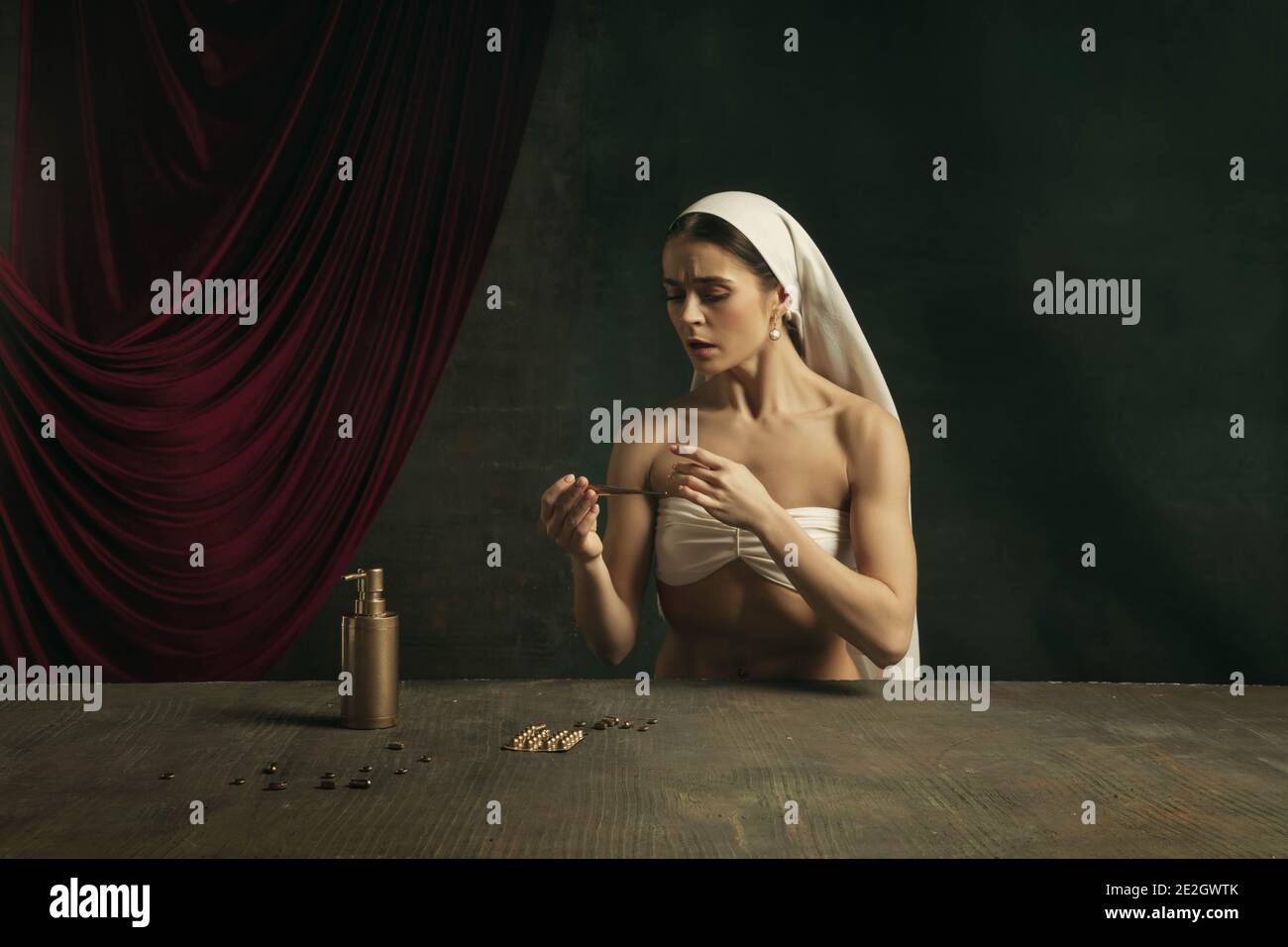 Moderno remake di opere d'arte classica con tema coronavirus - giovane donna medievale su sfondo scuro sente la febbre, prendendo pillole colorate in oro. Concetto di coronavirus, pandemia, creatività. Foto Stock