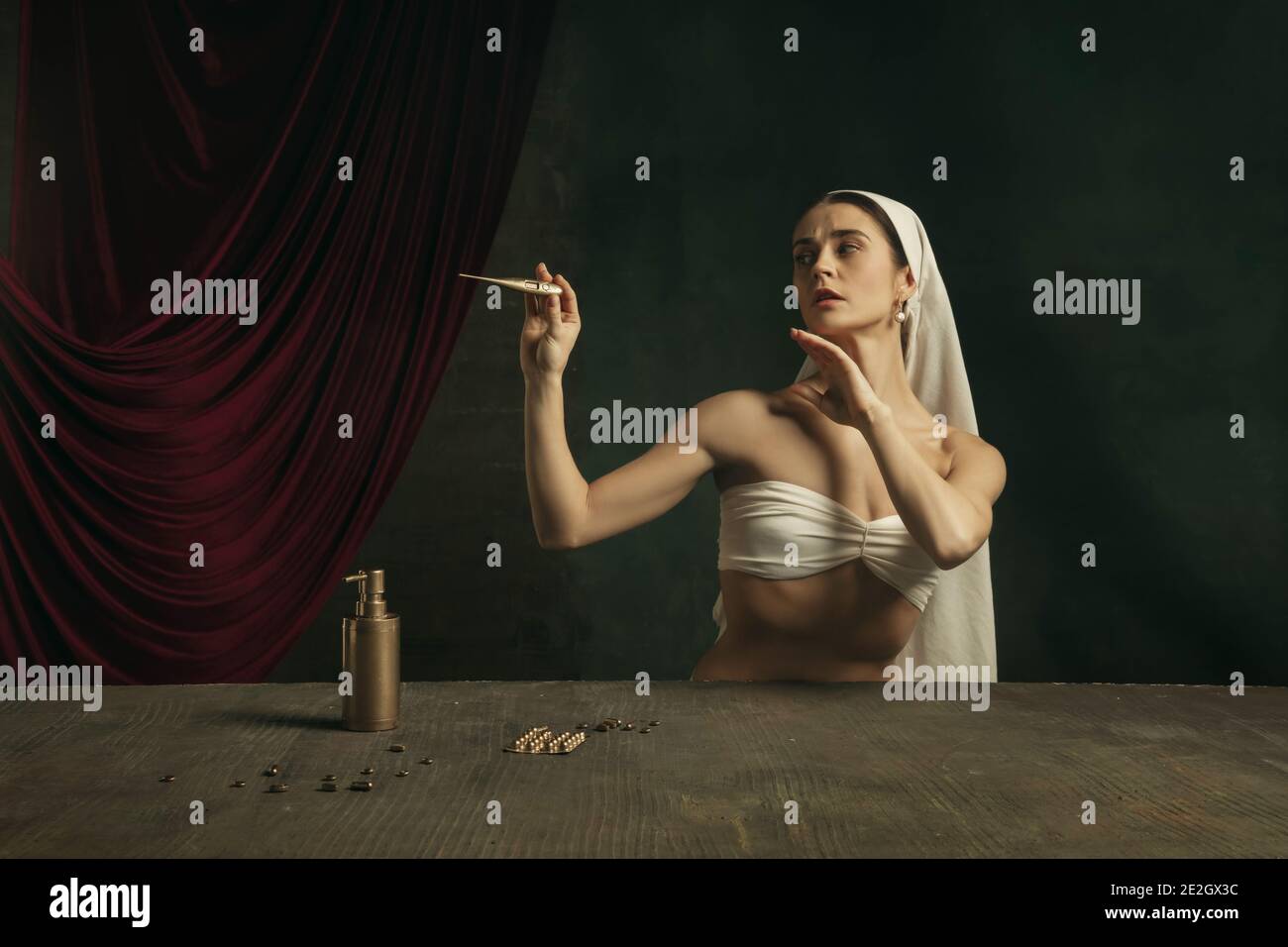 Moderno remake di opere d'arte classica con tema coronavirus - giovane donna medievale su sfondo scuro sente la febbre, prendendo pillole colorate in oro. Concetto di coronavirus, pandemia, creatività. Foto Stock