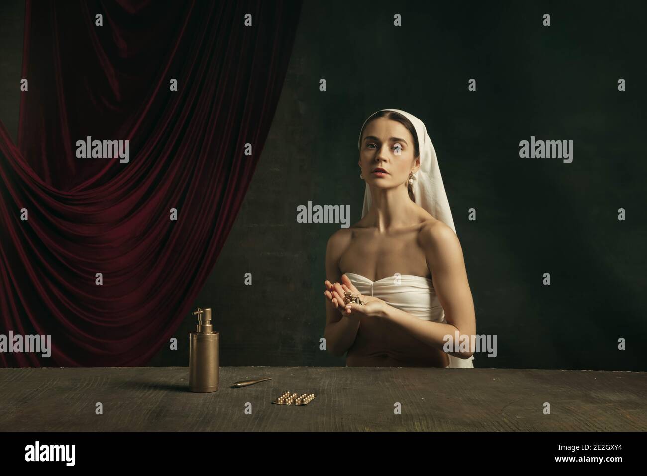 Sofferenza. Moderna remake di opere d'arte classica con tema coronavirus - giovane donna medievale su sfondo scuro in posa con medicina d'oro, pillole. Concetto di coronavirus, pandemia, creatività. Foto Stock